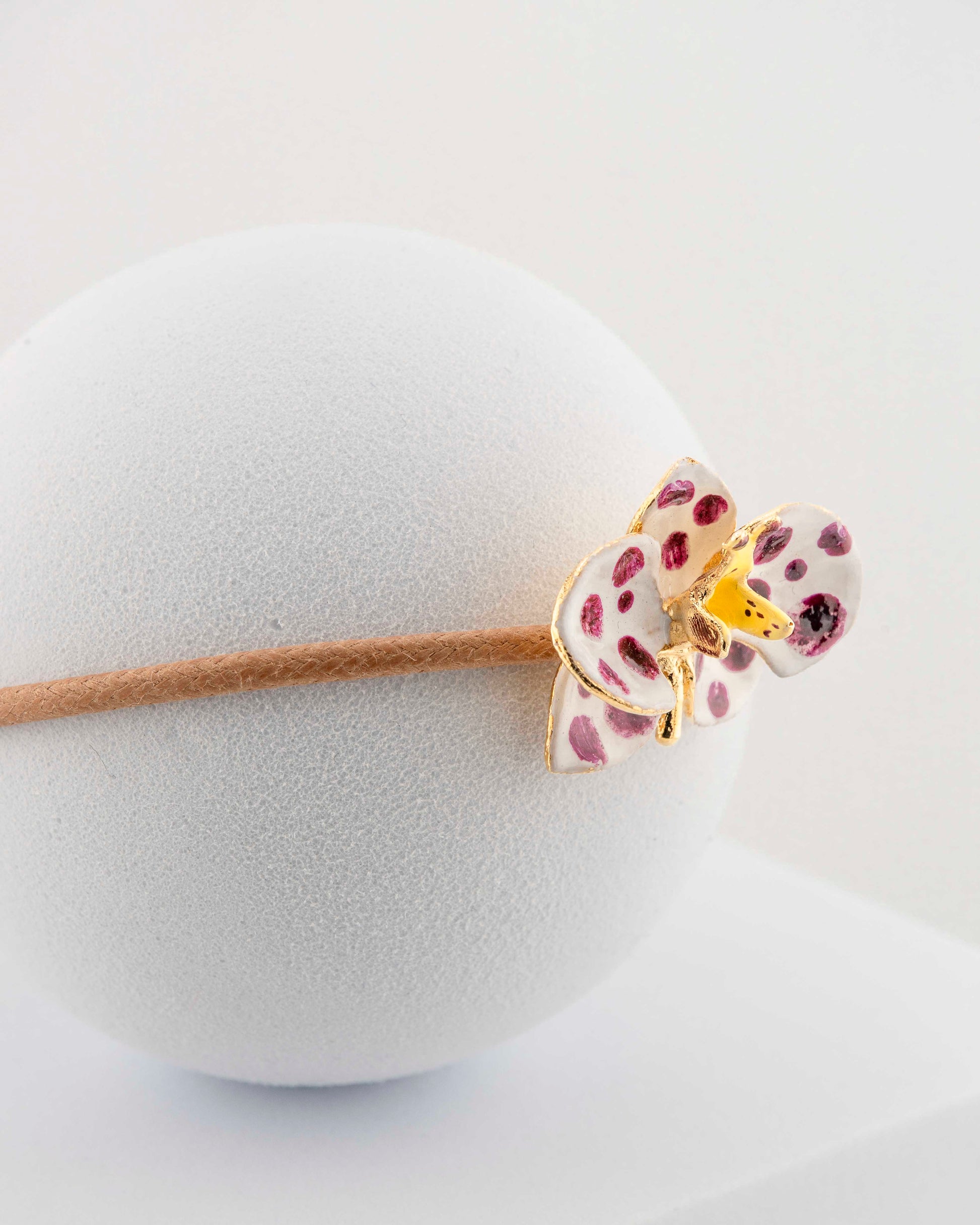 Handcrafted bracelet with adjustable cord and orchid pendant in 18K gold-plated bronze.
Each piece is hand-painted with enamel in Tuscany — unique and unrepeatable.