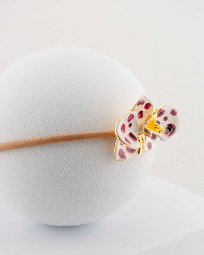 Handcrafted bracelet with adjustable cord and orchid pendant in 18K gold-plated bronze.
Each piece is hand-painted with enamel in Tuscany — unique and unrepeatable.