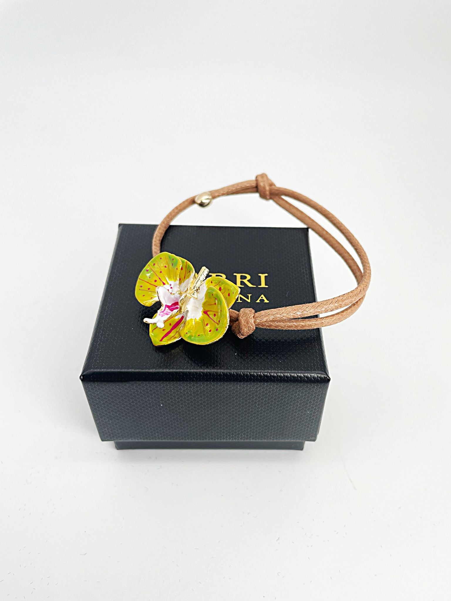 Handcrafted bracelet with adjustable cord and orchid pendant in 18K gold-plated bronze.
Each piece is hand-painted with enamel in Tuscany — unique and unrepeatable.