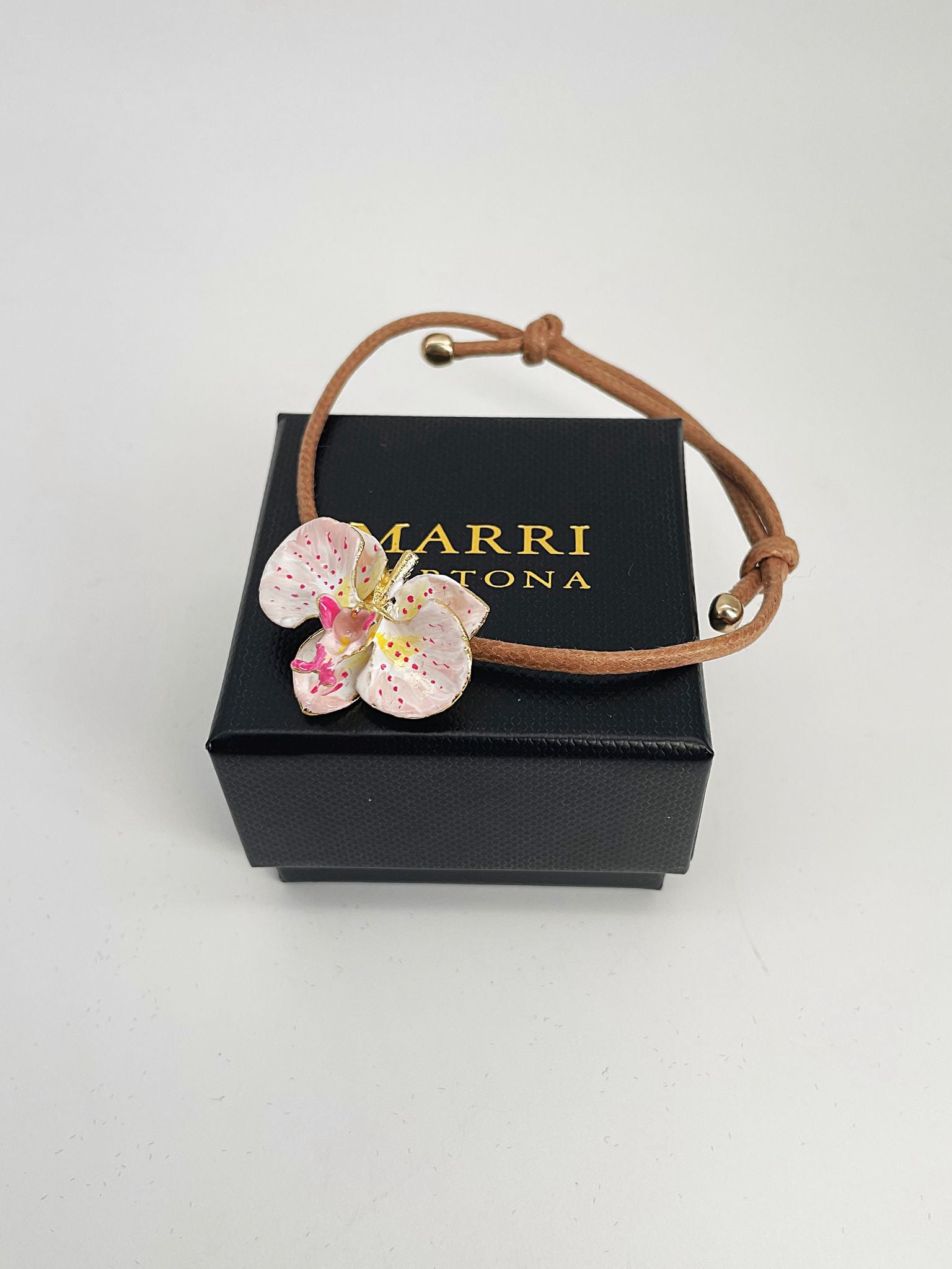 Handcrafted bracelet with adjustable cord and orchid pendant in 18K gold-plated bronze.
Each piece is hand-painted with enamel in Tuscany — unique and unrepeatable.