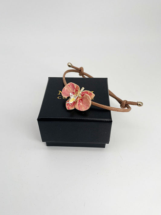 Handcrafted bracelet with adjustable cord and orchid pendant in 18K gold-plated bronze.
Each piece is hand-painted with enamel in Tuscany — unique and unrepeatable.